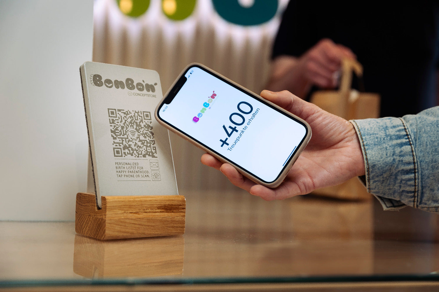 Beispielbild: Das Smartphone wird an den NFC Aufsteller gehalten, es öffnet sich ein Pop Up Link, den Sie anklicken können. 
